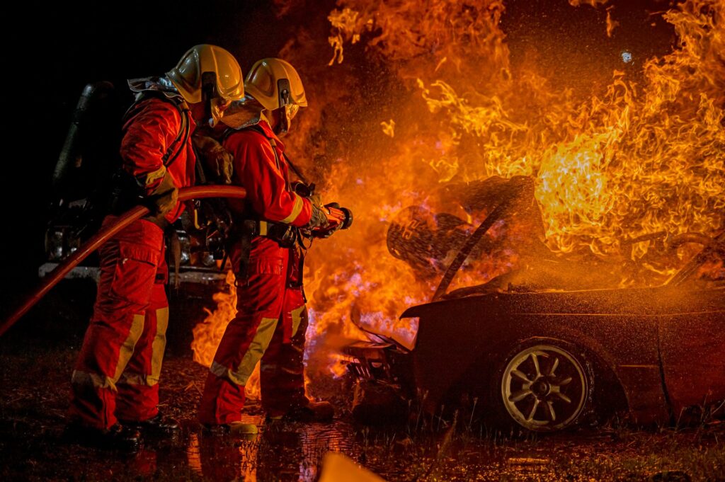 a-firefighter-in-training-sprays-a-burning-car-with-a-fire-hose-nozzle-e1696820081327.jpg